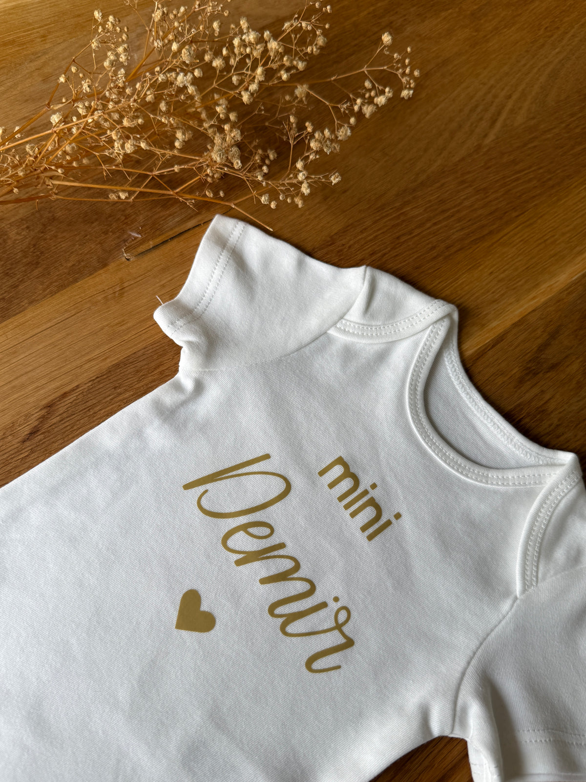Personalisierbares Baby Body aus Bio-Baumwolle mit Namen in Goldschrift.